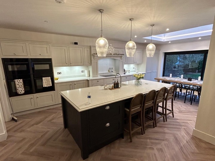 Open plan kitchen diner with a dark island, glass pendant lights and a roof lantern