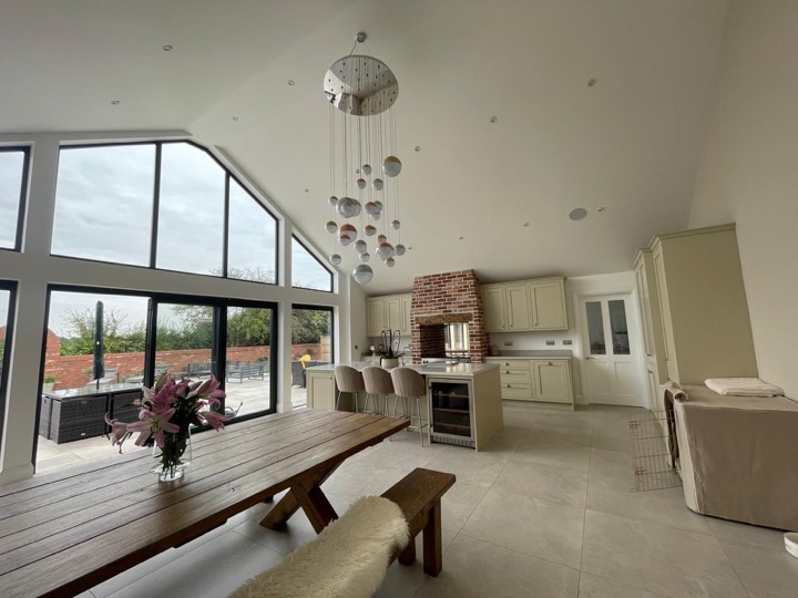 Open plan kitchen diner with a vaulted ceiling and a glazed gable opening onto the patio