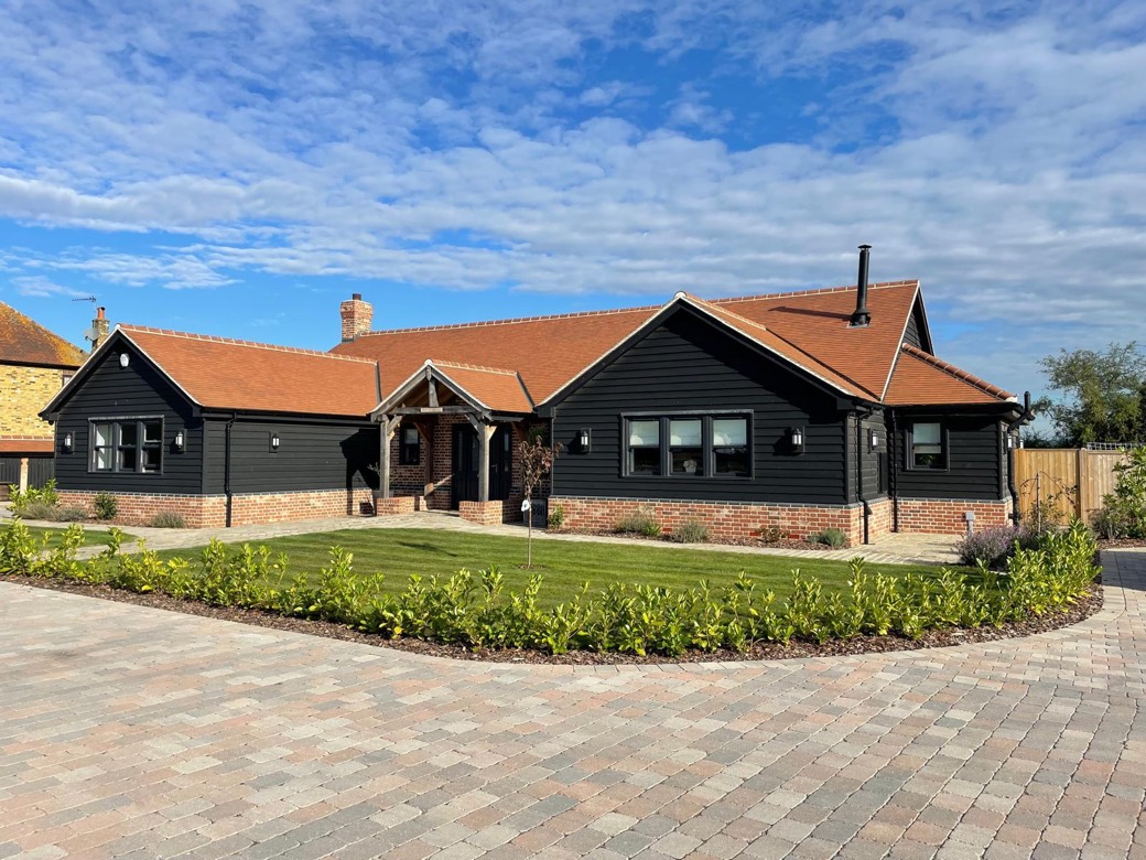 Black weatherboarded bungalow with clay tiles, an oak framed porch and a landscaped front garden